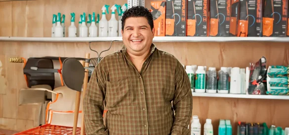 Microempresario posa en su negocio rodeado de productos para el hogar, reflejando optimismo empresarial y perspectivas económicas positivas para las mipymes en 2025.