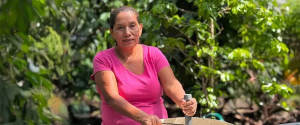 Mujer trabaja en entorno rural rodeada de vegetación, reflejando economía circular y emprendimiento sostenible en microempresas locales de El Salvador.