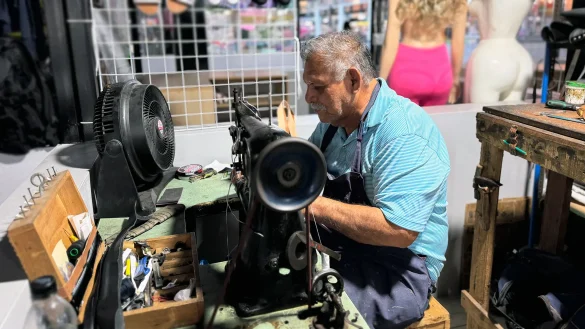 Hombre trabaja con máquina de coser en taller textil, reflejando empleo informal y producción artesanal en mipymes salvadoreñas