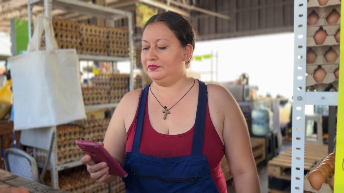 Emprendedora MYPE revisando su celular en su negocio, ejemplo del uso de herramientas digitales e inteligencia artificial