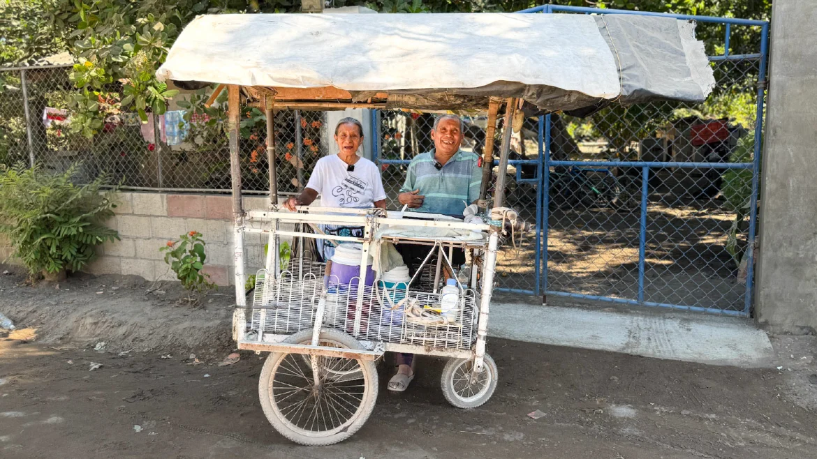 Dos adultos mayores atienden carrito de venta de bebidas en comunidad de El Salvador, ejemplo de microemprendimiento y economía informal rural